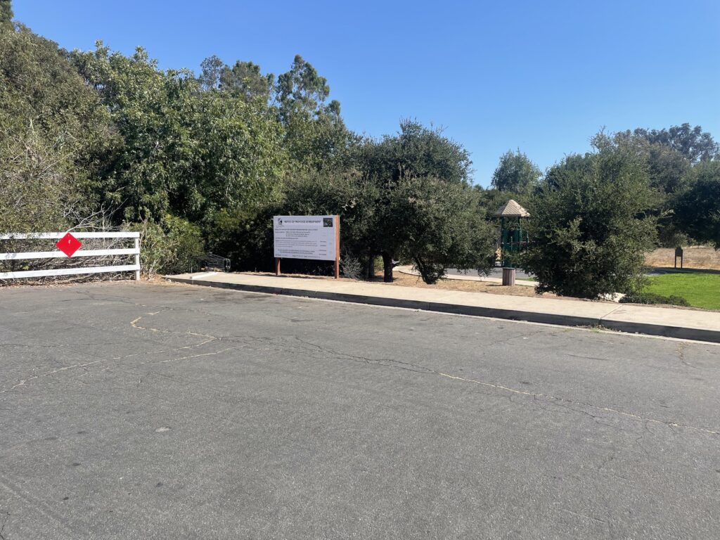 A sign on the side of a road near some trees.